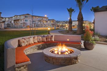 an outdoor fire pit at night with an apartment building in the background